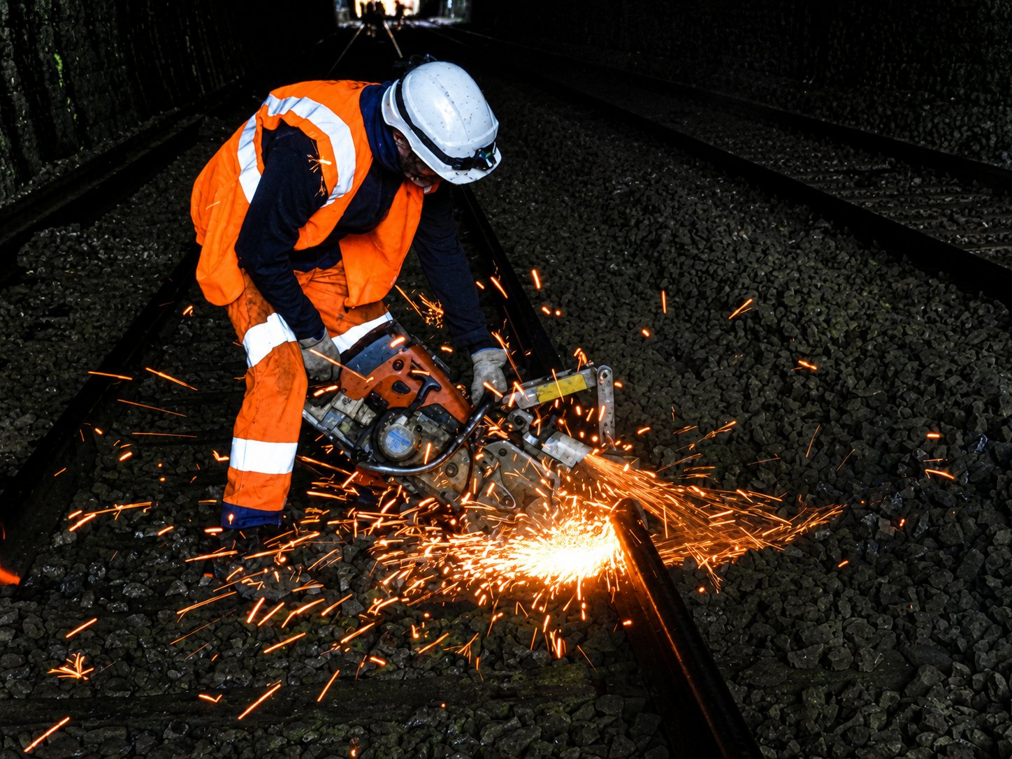 Agent TVF tronçonnant un rail en tunnel, gerbe d'étincelles